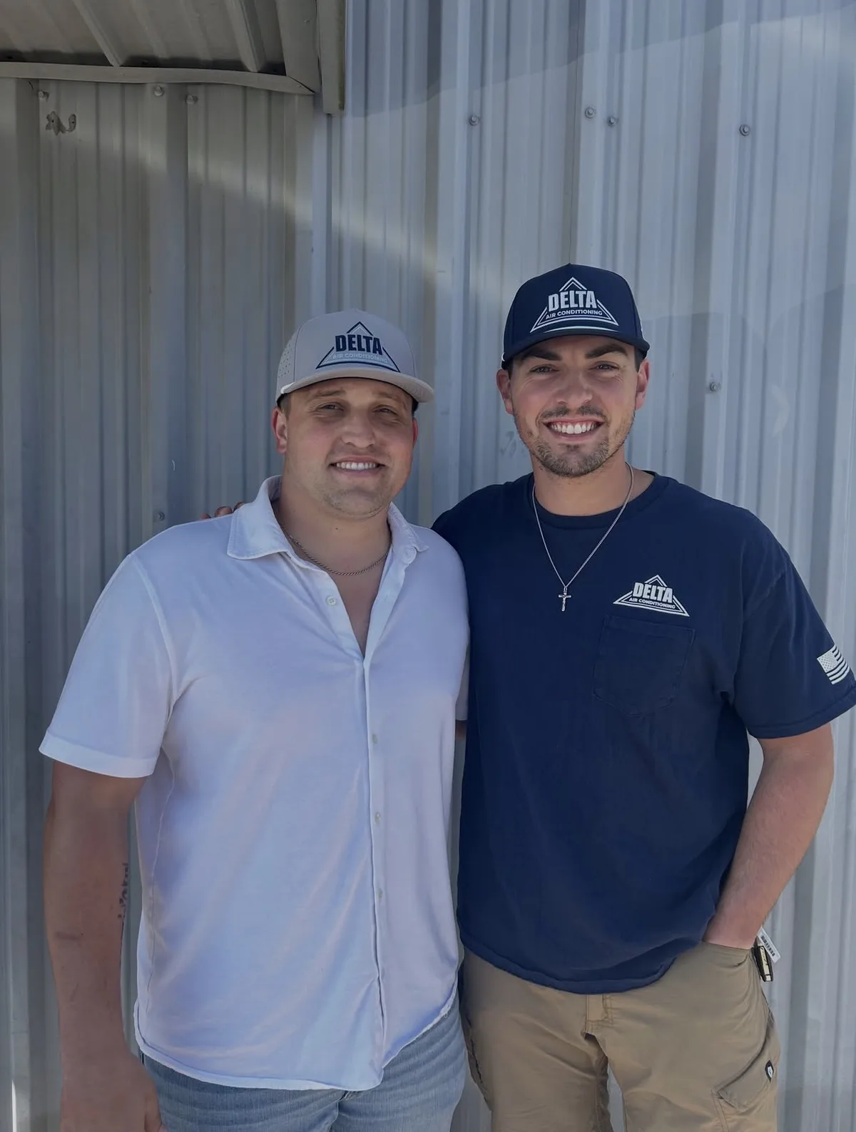 Two Delta Air Conditioning team members wearing the grey and navy caps